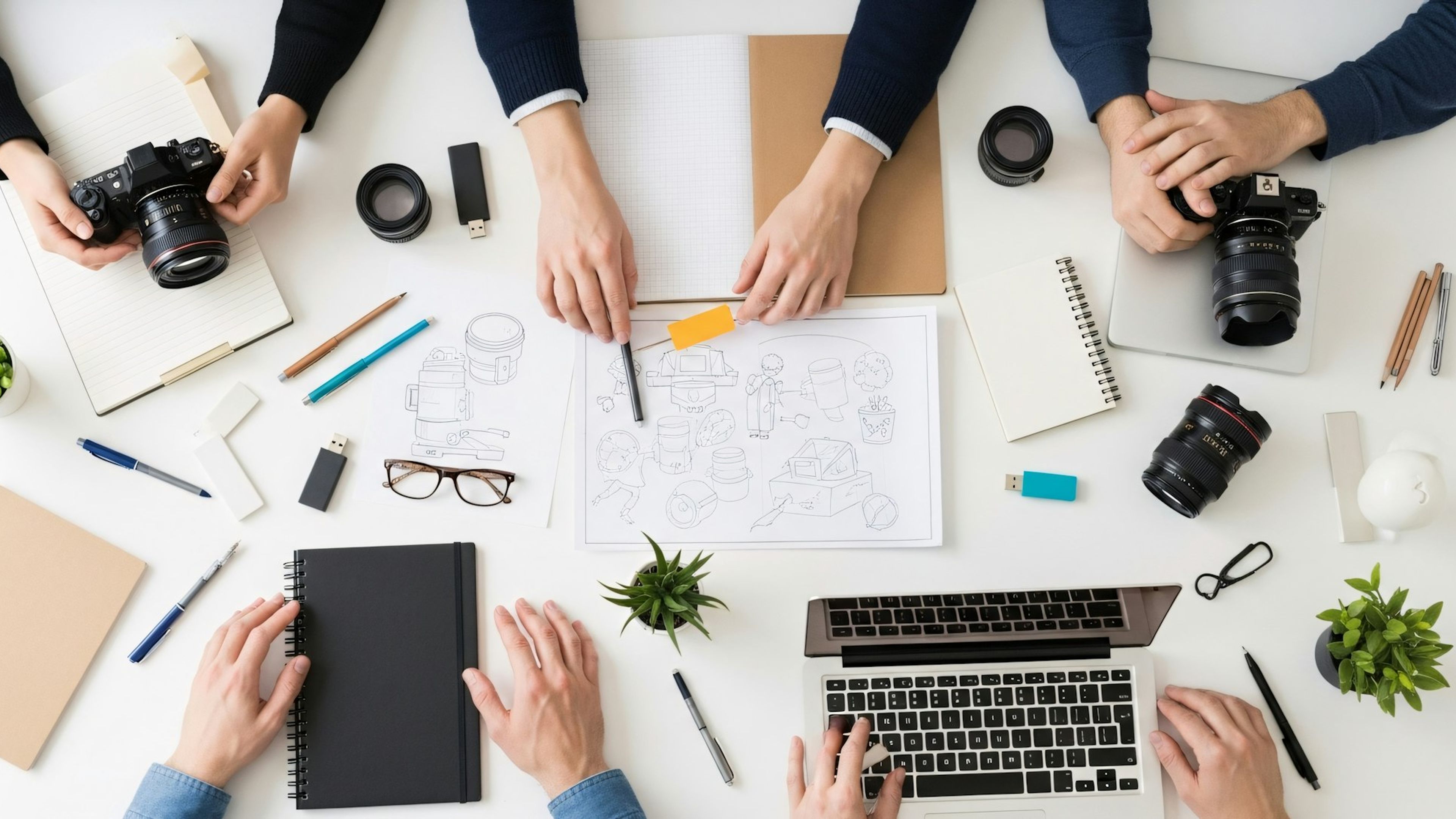 Hands sketching wireframes around a laptop