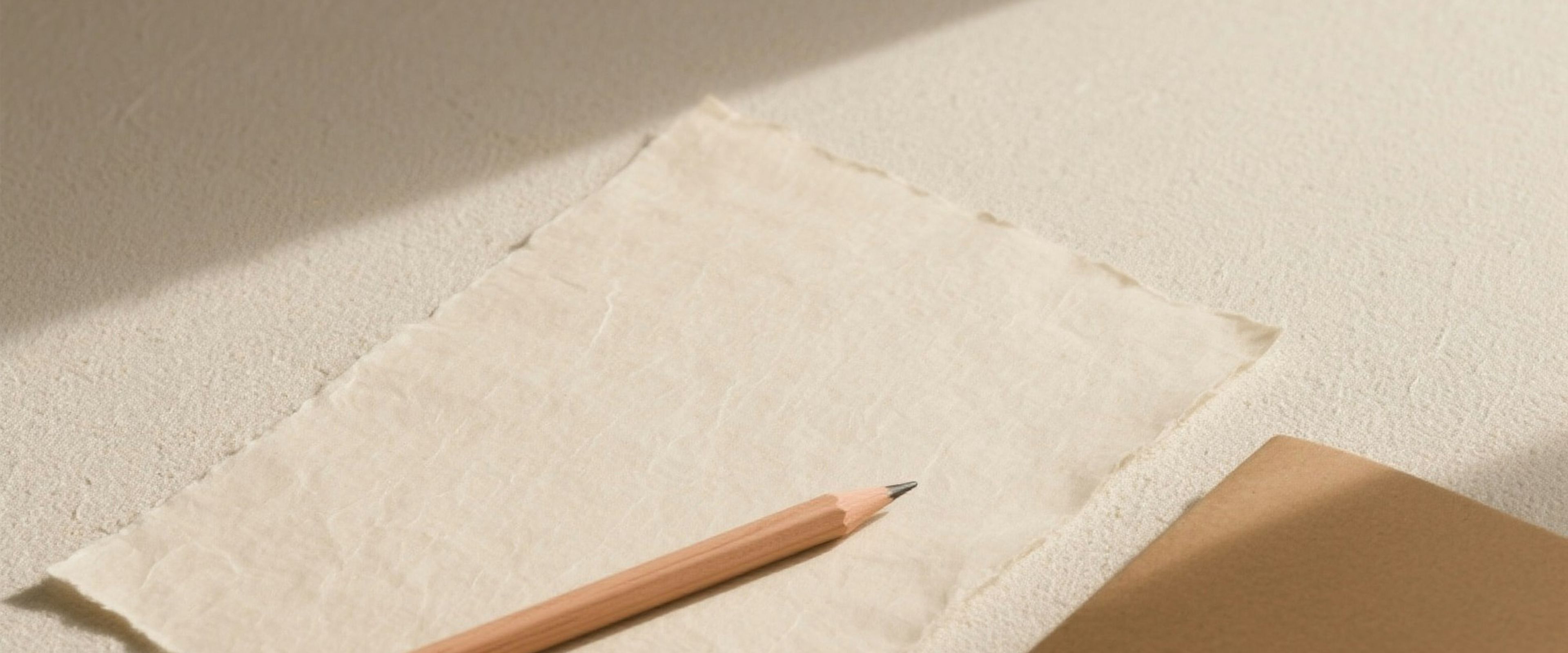 An open notebook and pencil on a warm linen desk