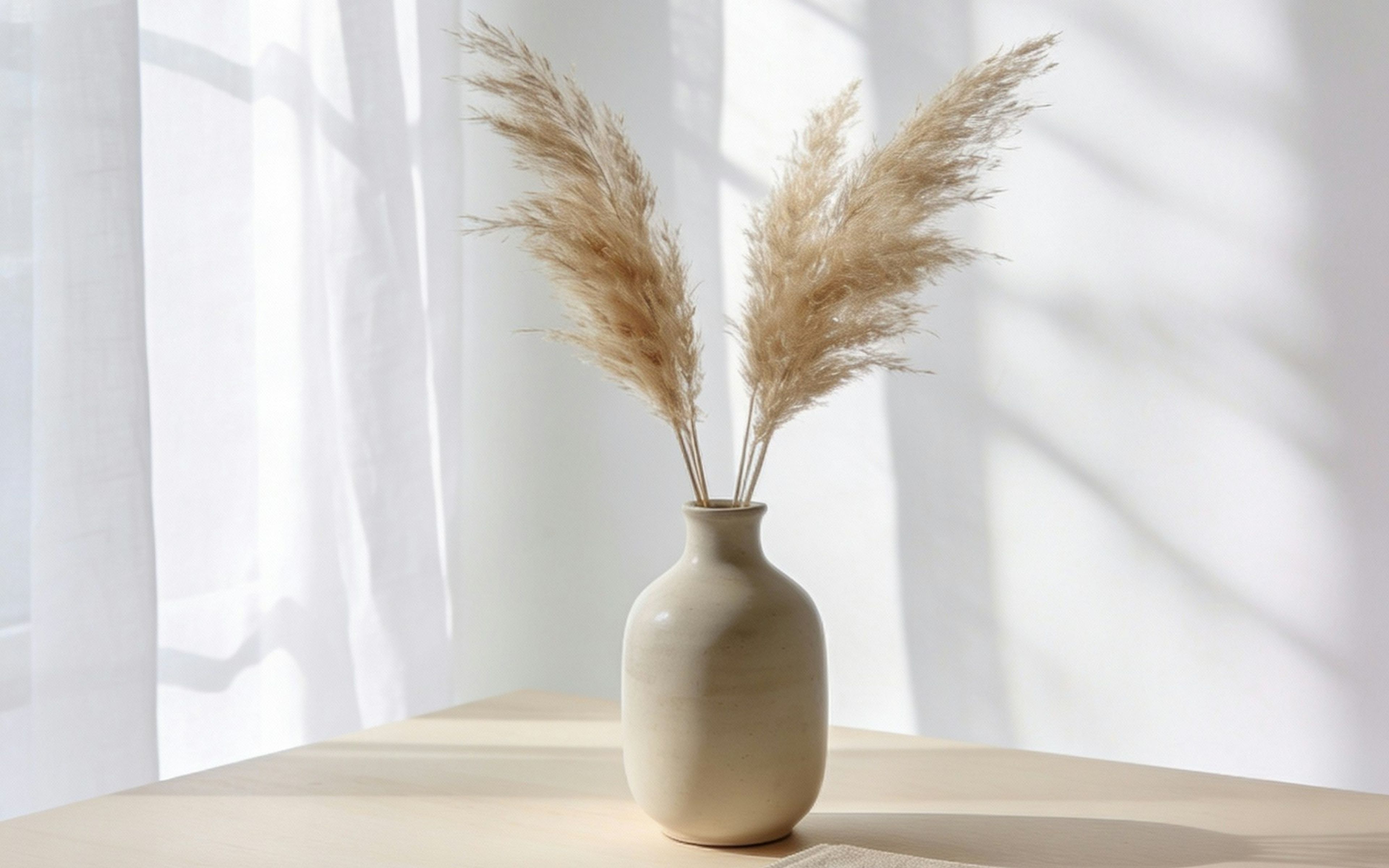Dried grasses in a ceramic vase on a sunlit shelf