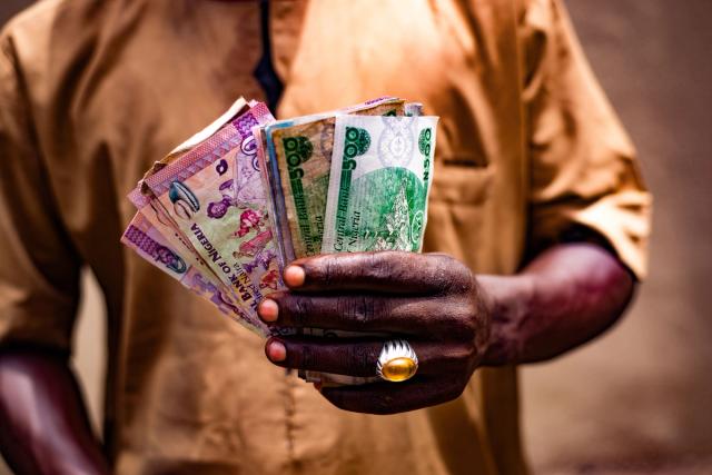 A person holding a fan of Nigerian naira banknotes.