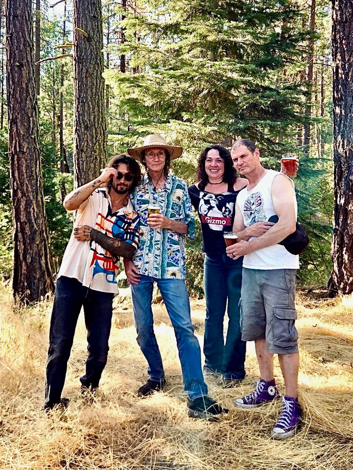 ELT posing in forest, drinks in hand.