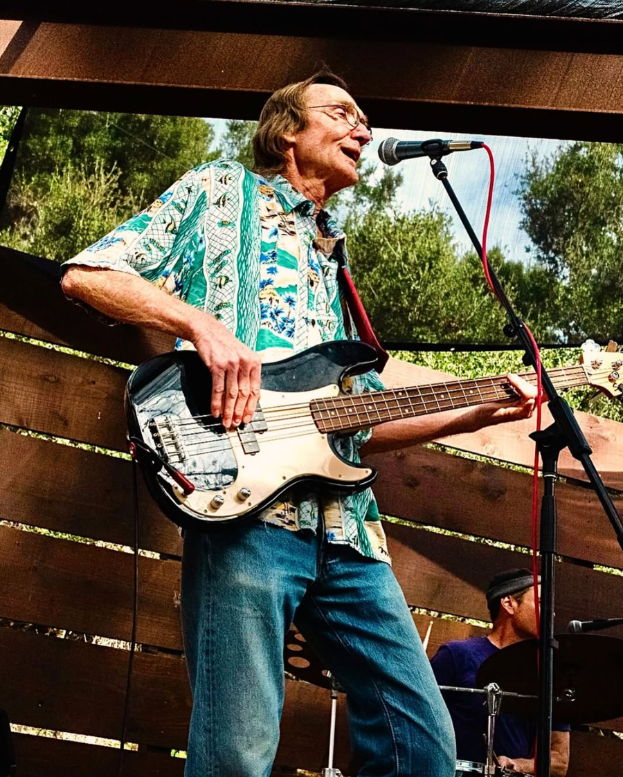 Geert playing bass and singing at an outdoor show.