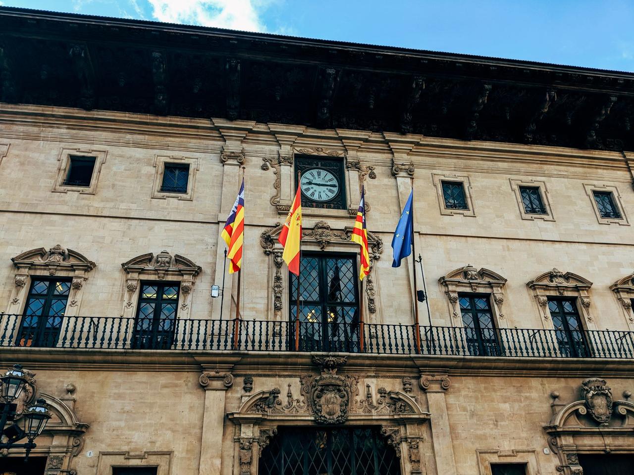 Facade of Palma's City Hall with flags and historic architecture.