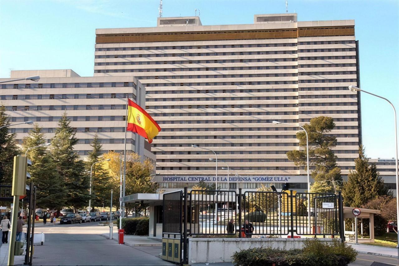 Fachada del Hospital Central de la Defensa Gómez Ulla en Madrid con bandera española, acceso principal vallado, edificios de