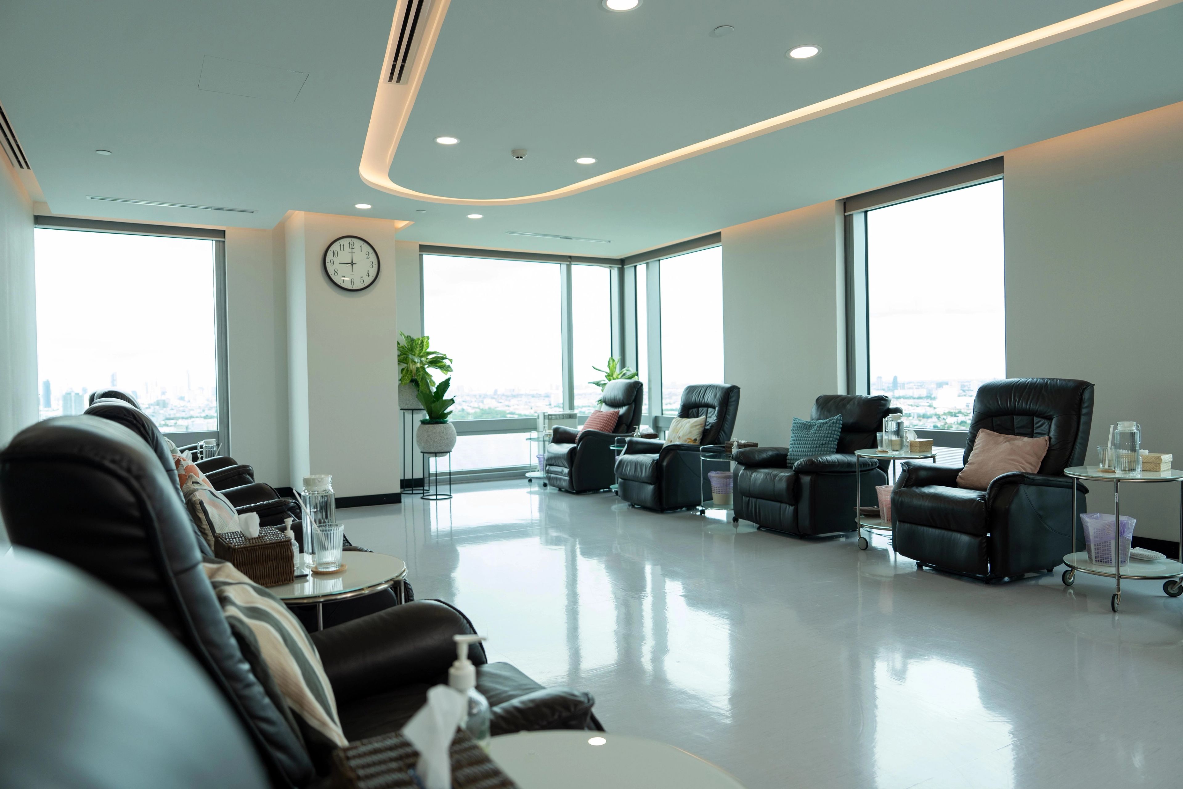 Treatment room at Verita Life with eight black leather armchairs with different coloured cushions and small tables between.