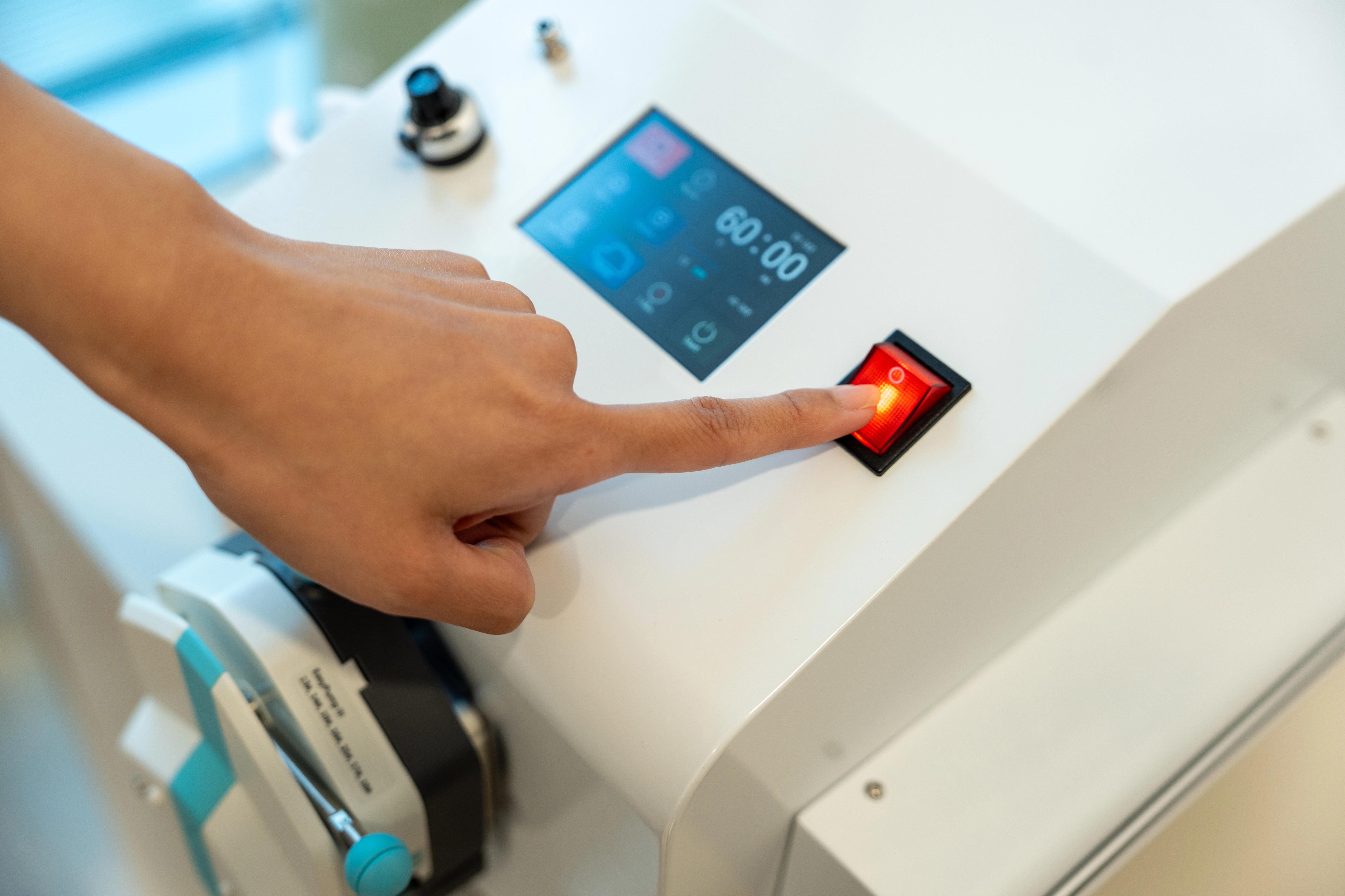 Index finger presses a red button on a EBBO machine.