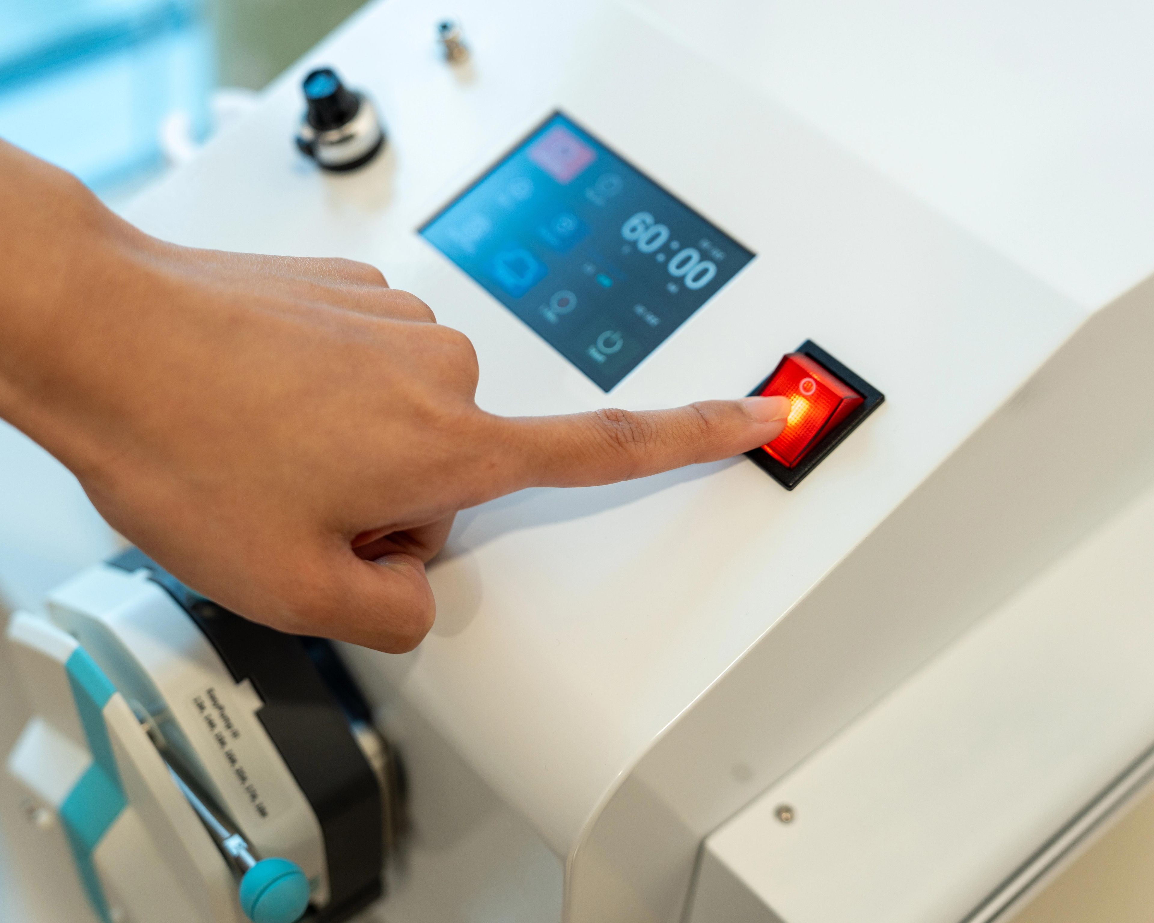 Index finger presses a red button on a EBBO machine.