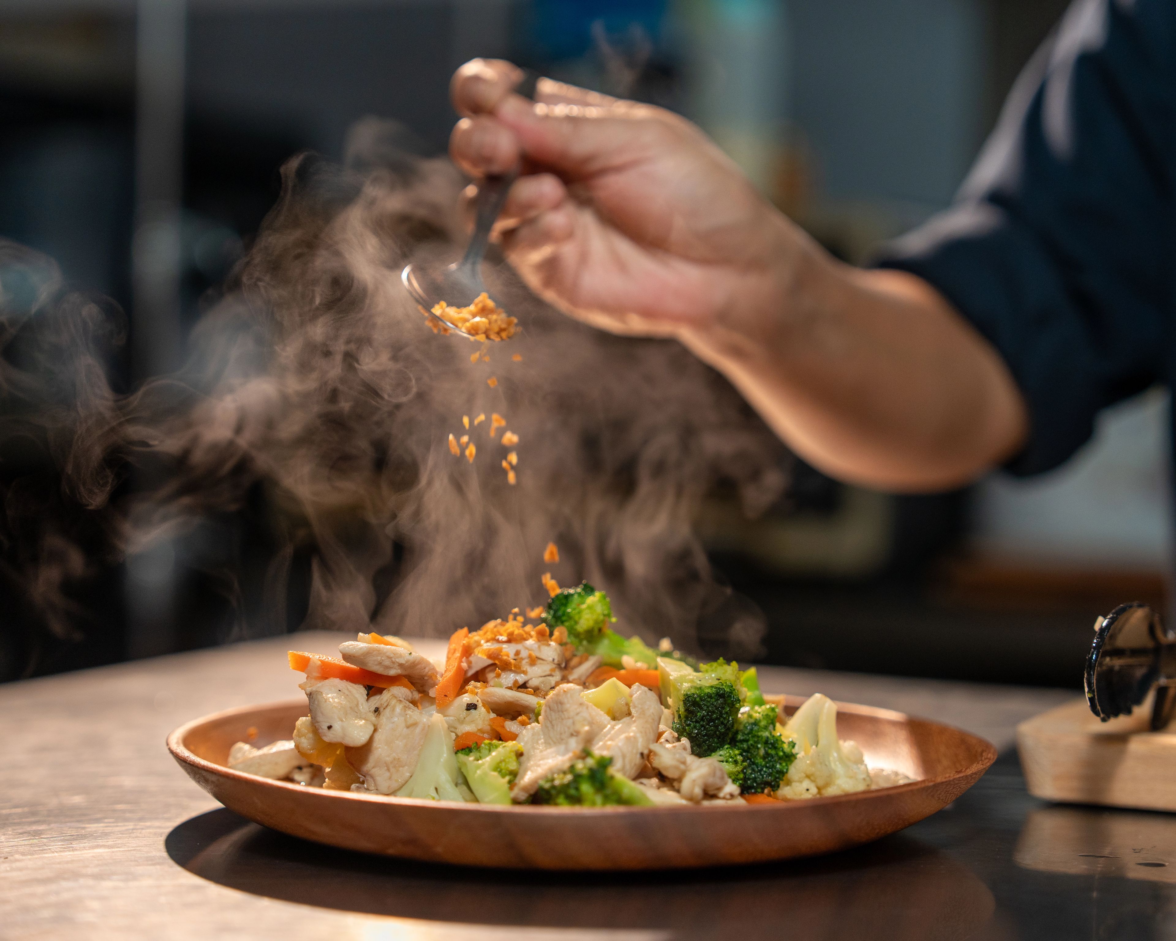 A close up of a plate of chicken and vegetables with steam rising from it.