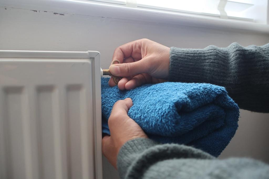 A person adjusts the temperature on a radiator