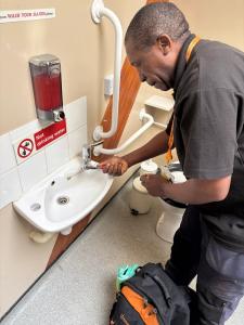 A plumber fits a tap insert in a school bathroom