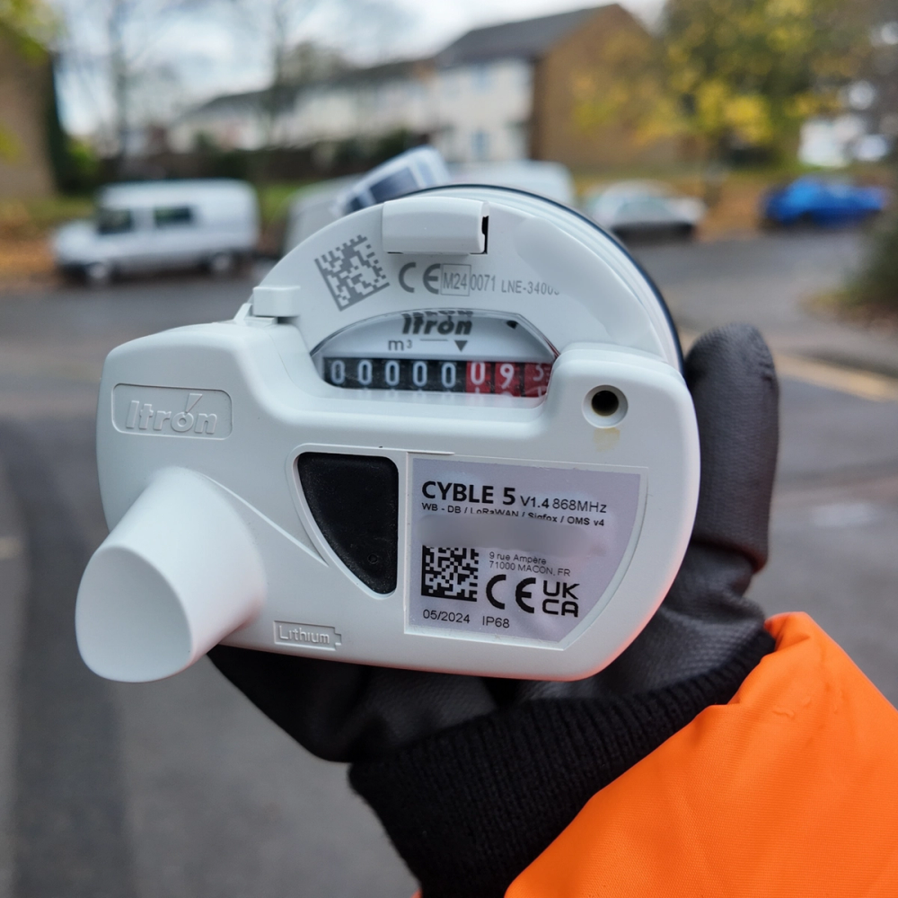 Close up photograph of a South East Water employee holding a white water meter.
