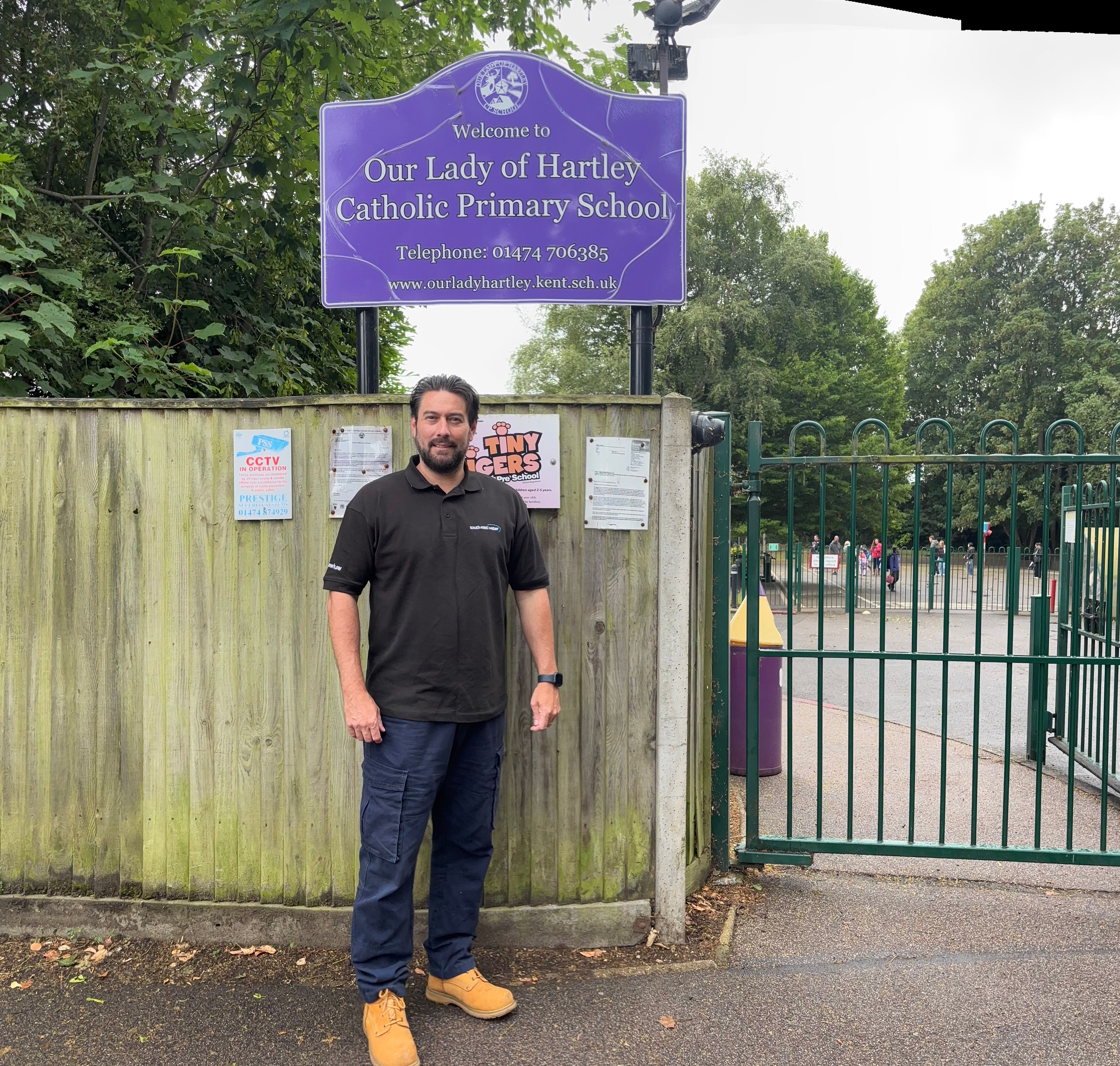 Our delivery partner stands next to the school sign for Our Lady of Hartley School