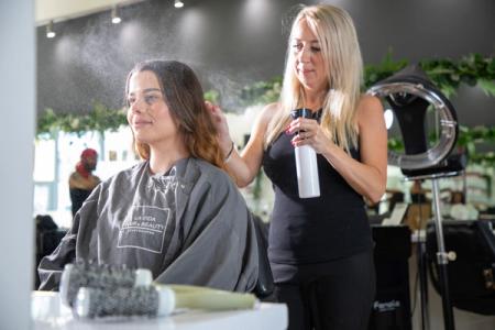 Hairdresser using a spray water gun on her customer's hair