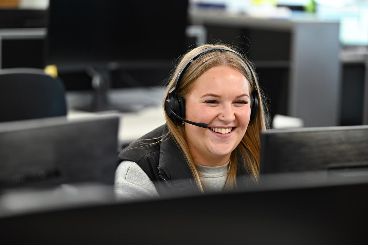 A customer service agent laughing on the phone with a customer