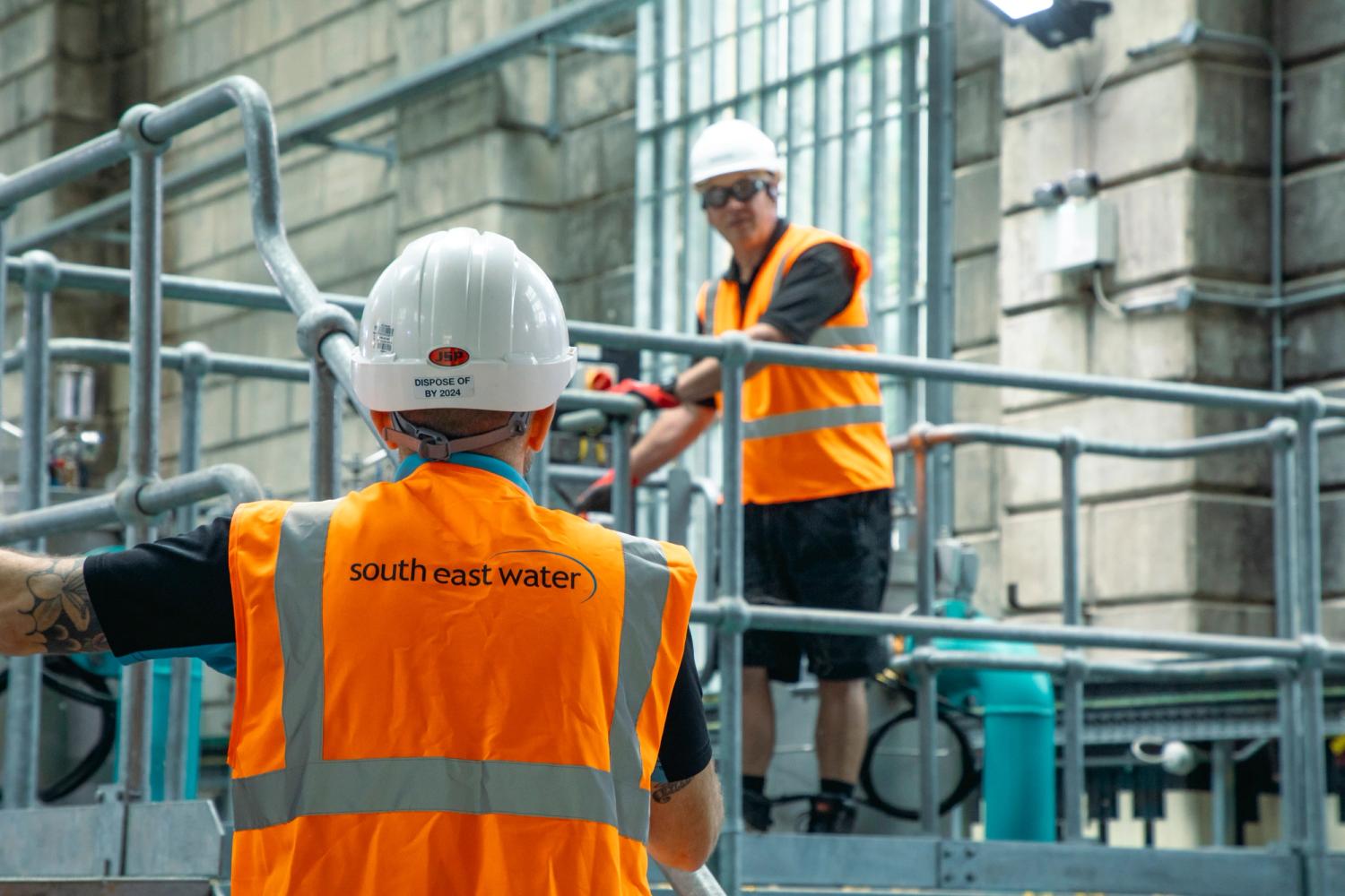 People in hi-vis look on at a water treatment works