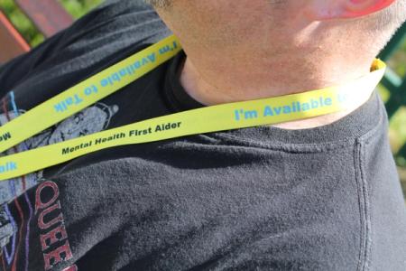 Yellow lanyard that has mental health first aider and I'm available written on it 