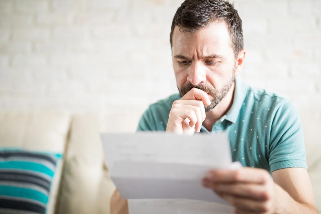 Photo of a person holding a white A4 sheet of paper that represents a household bill.
