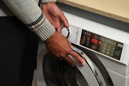 A person setting up their washing machine for an ECO cycle.