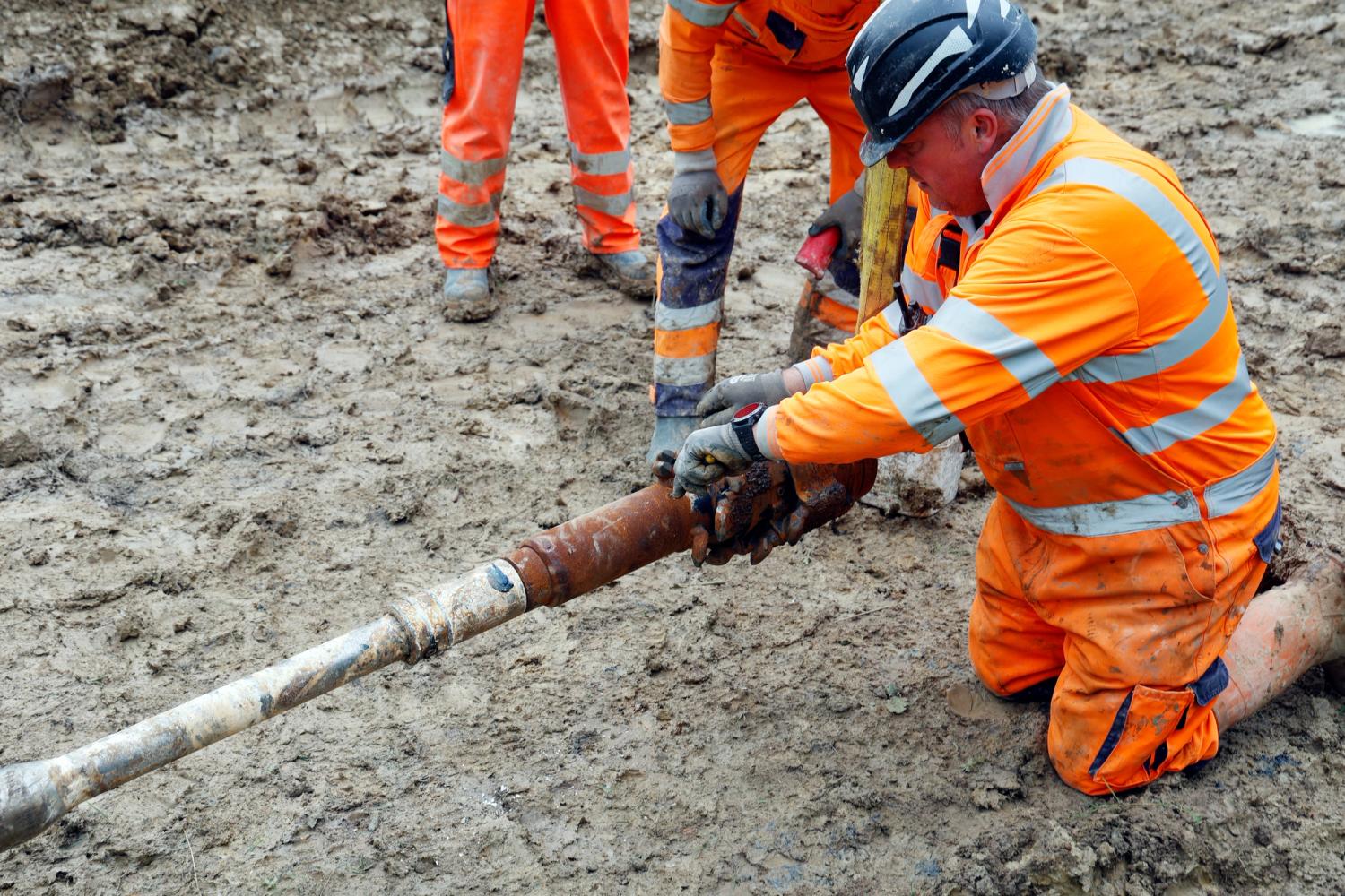 Photo of South East Water employees wearing high-vis workwear installing a new pipe line underground 