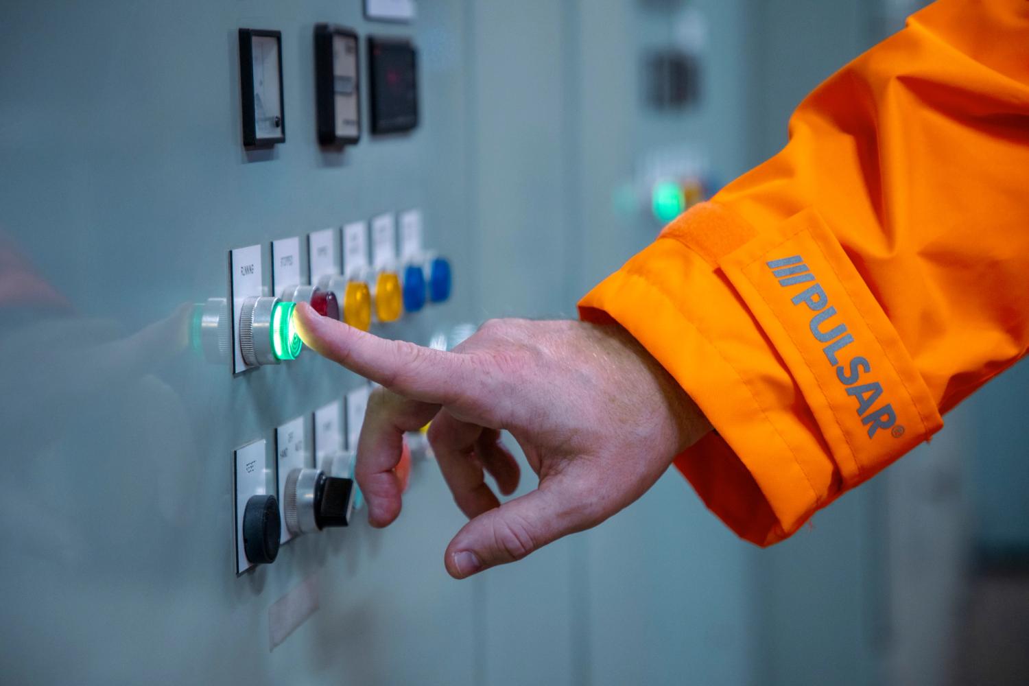 A man wearing high-visibility clothing pushes a button