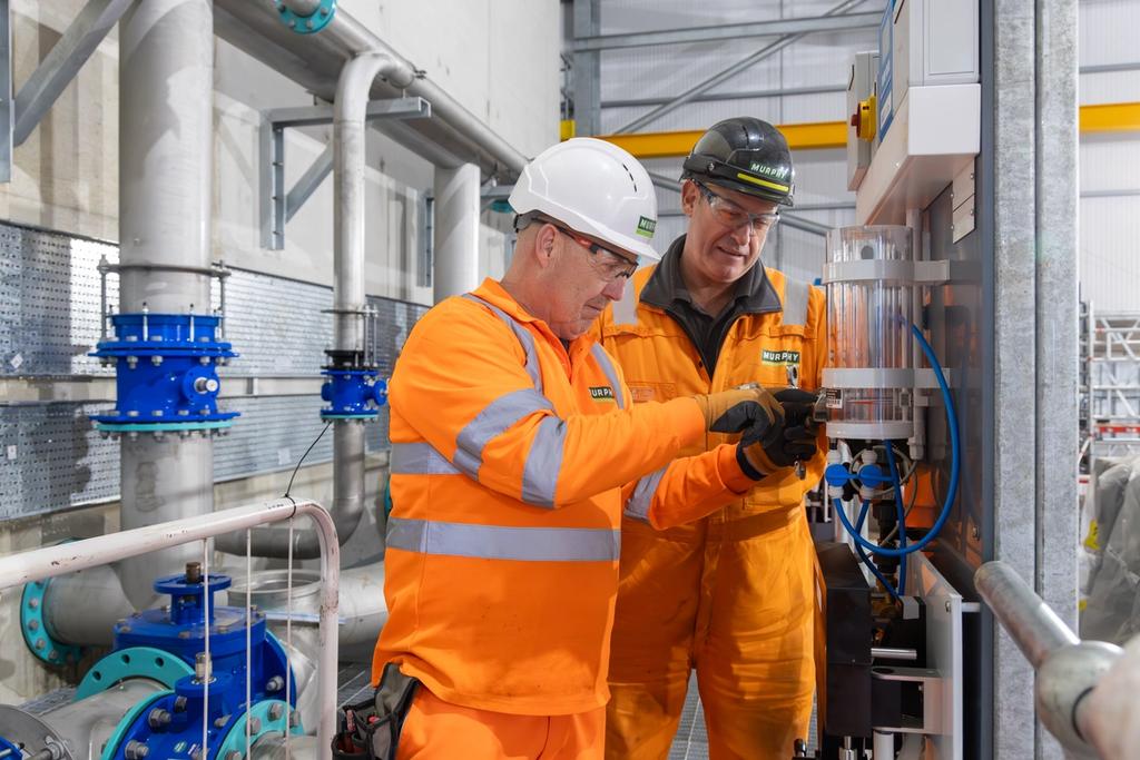Two workers attaching equipment to a wall