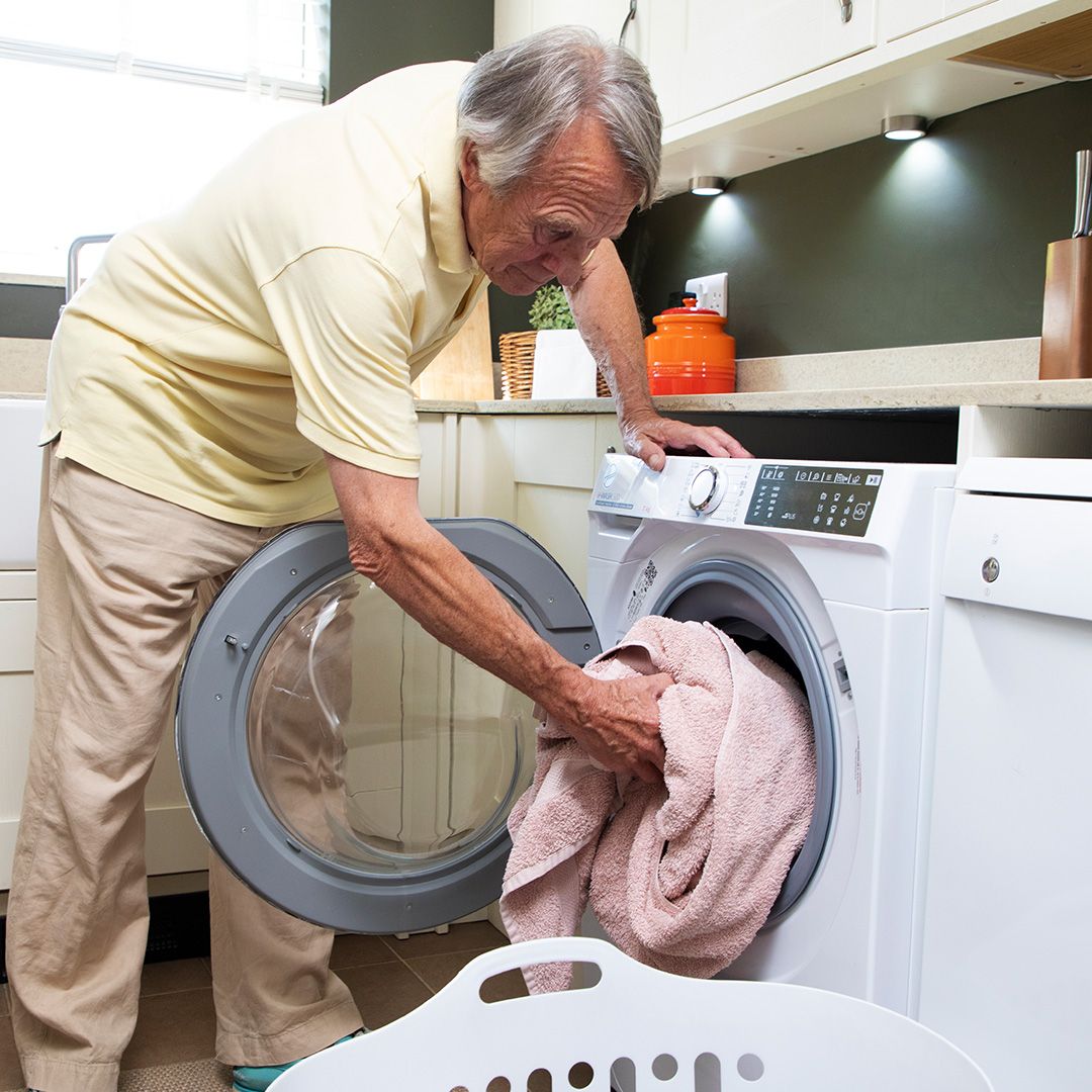 A man loading a washing machine with towels 