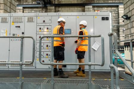 Two water treatment works technicians talking next to some equipment 