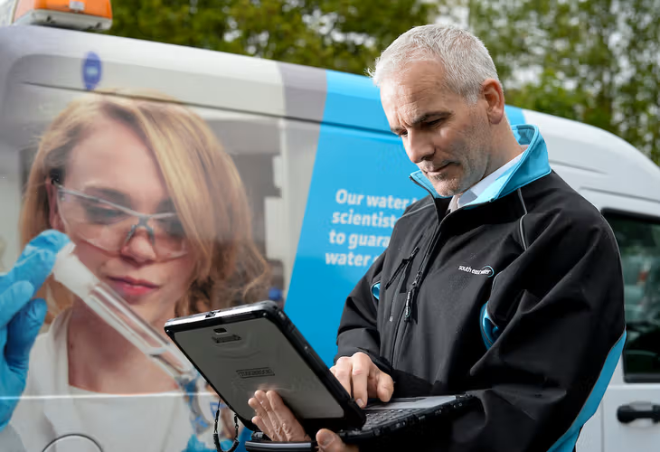 Man standing in front of South East Water with laptop 