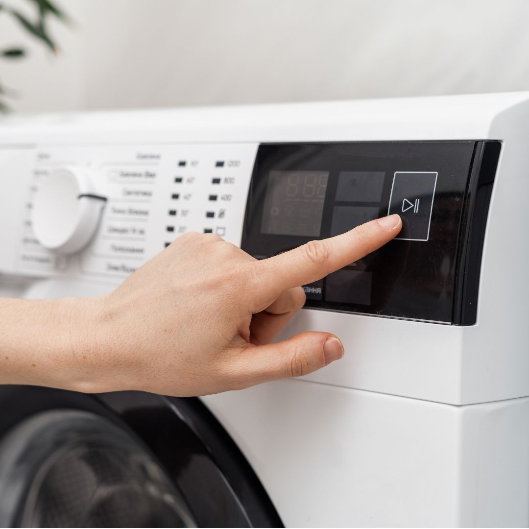 A person turning on a washing machine
