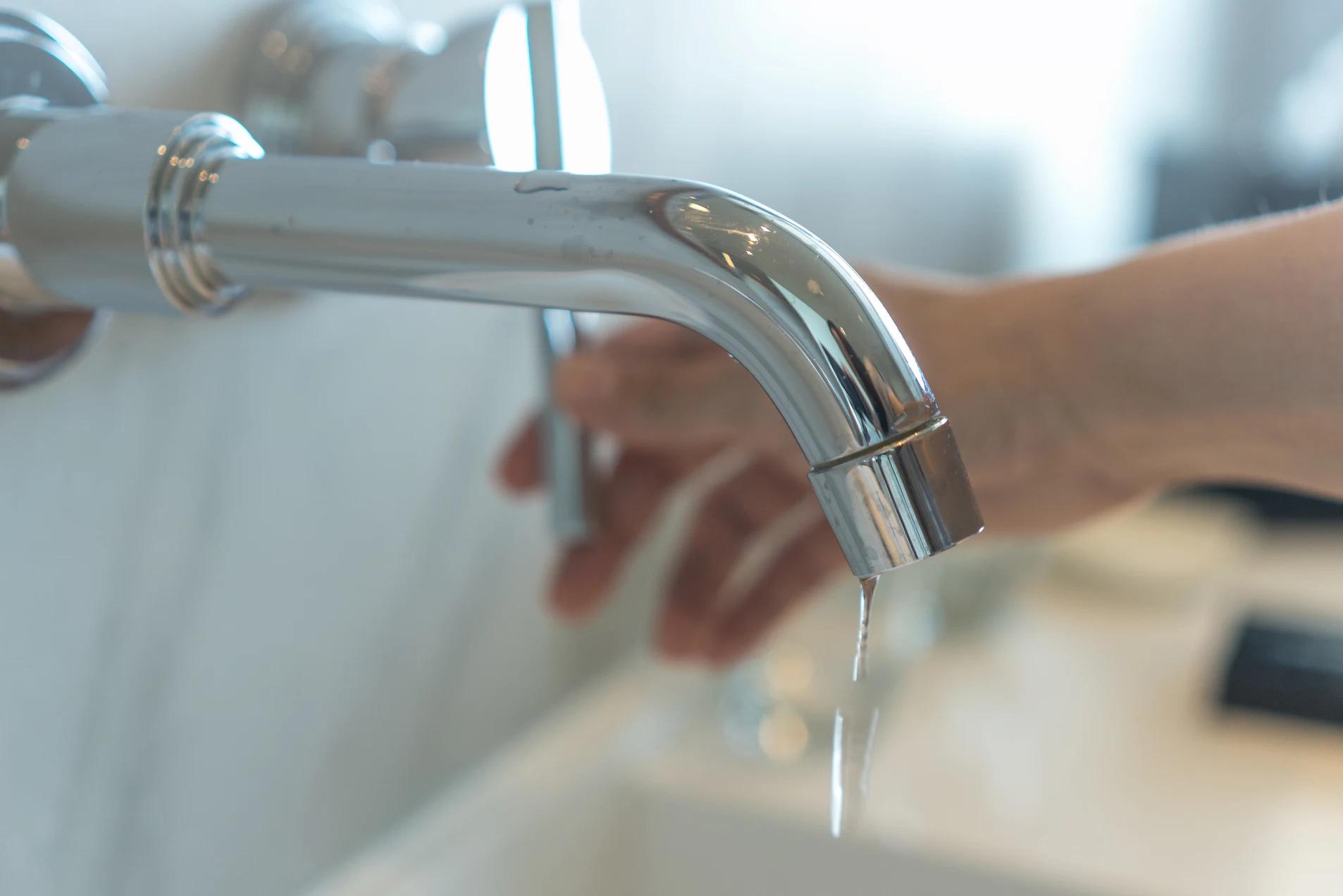 Image of someone turning off a dripping tap.