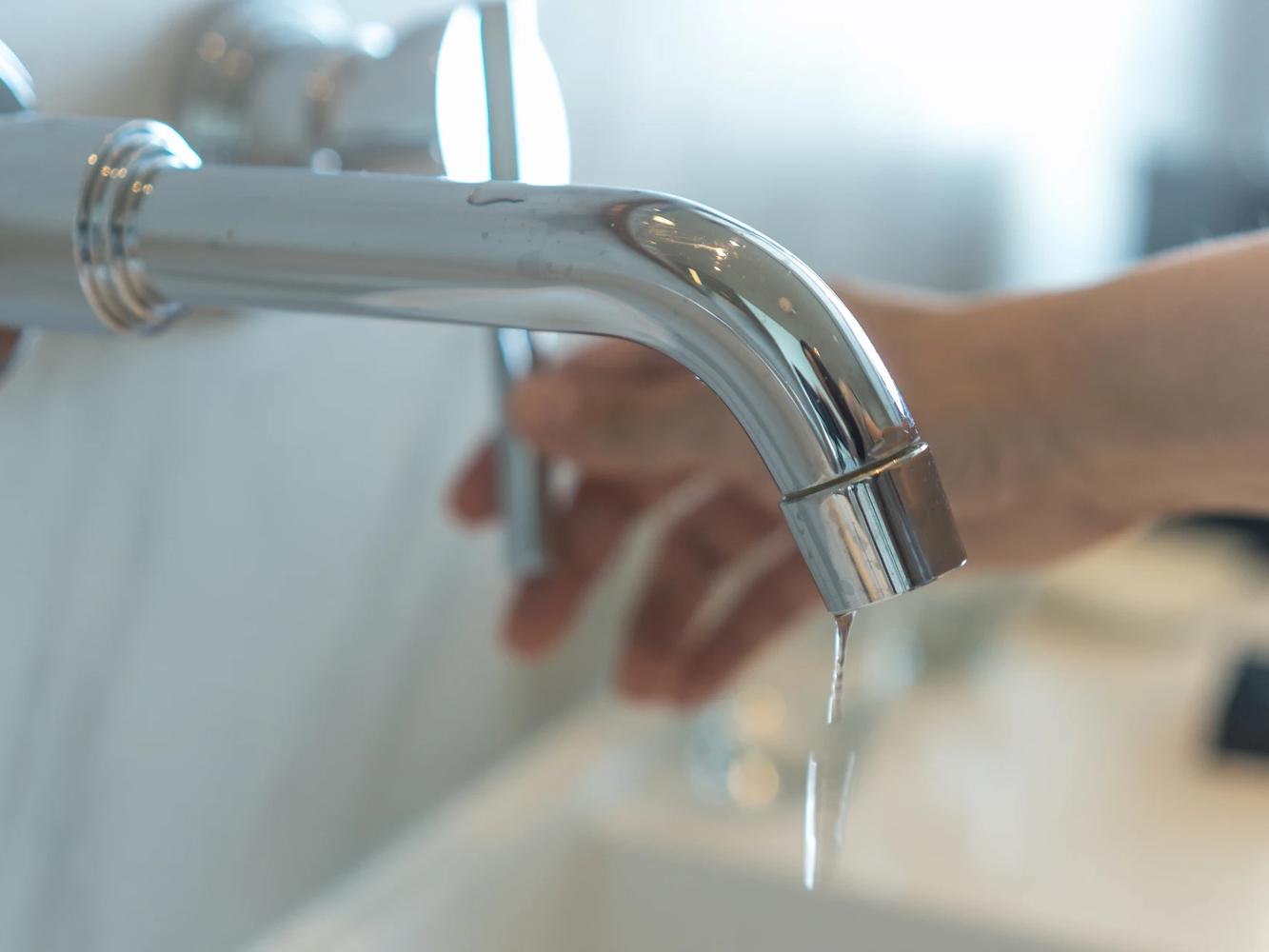 Image of someone turning off a dripping tap.