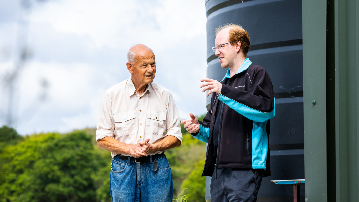 Photo of a South East Water environment employee chatting to a farmer with a large water tank in the background