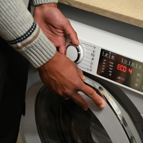 Image of a person setting the washing machine to eco-setting.