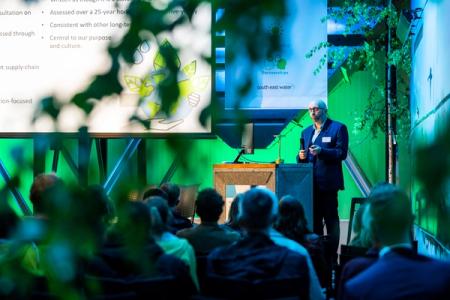 David Hinton presenting at the 24 Year Environment with green background and audience watching