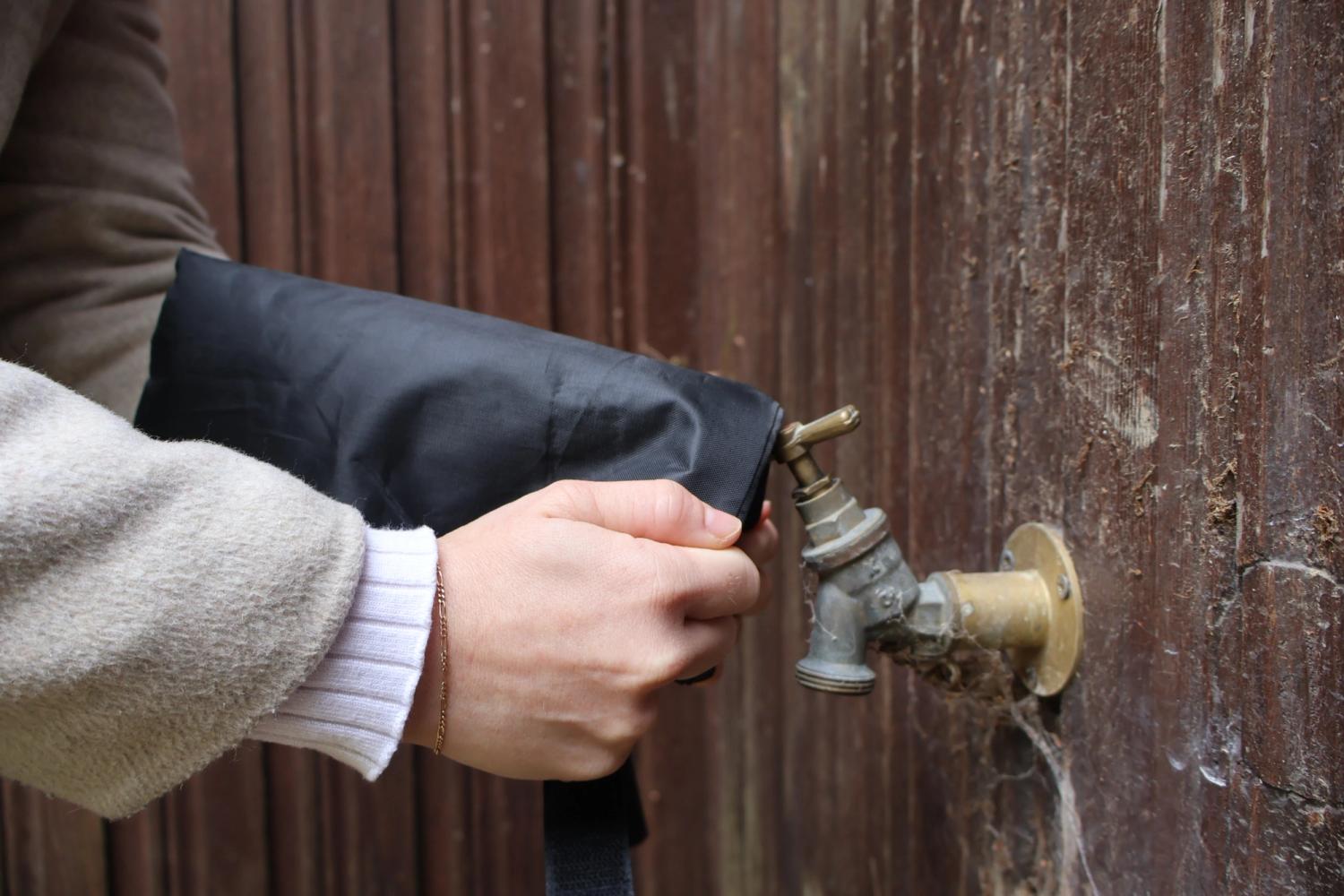 A woman's hand putting a tap jacket on top of an outdoor tap.