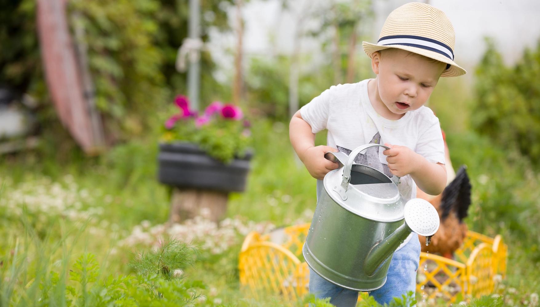 A child wearing a hat holding a watering can 