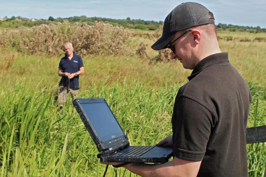 Man standing in field with laptop