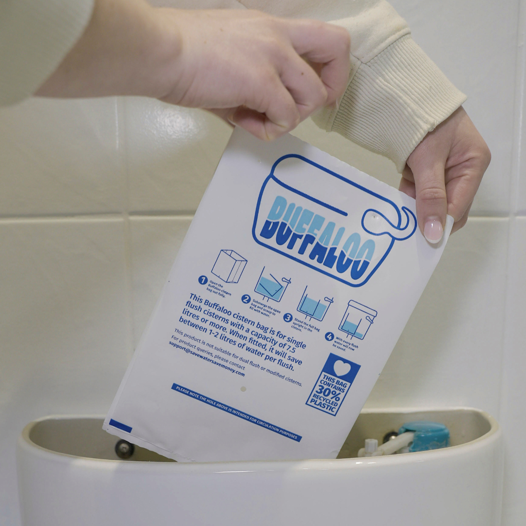 A person putting a Buffaloo Cistern Bag into the top of their toilet.