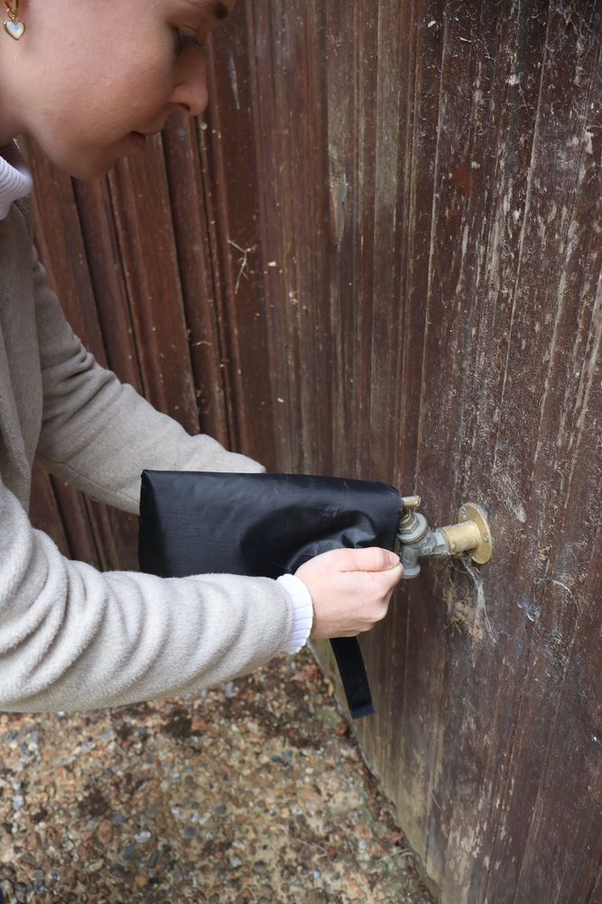 A woman's hand putting a tap jacket on top of an outdoor tap.