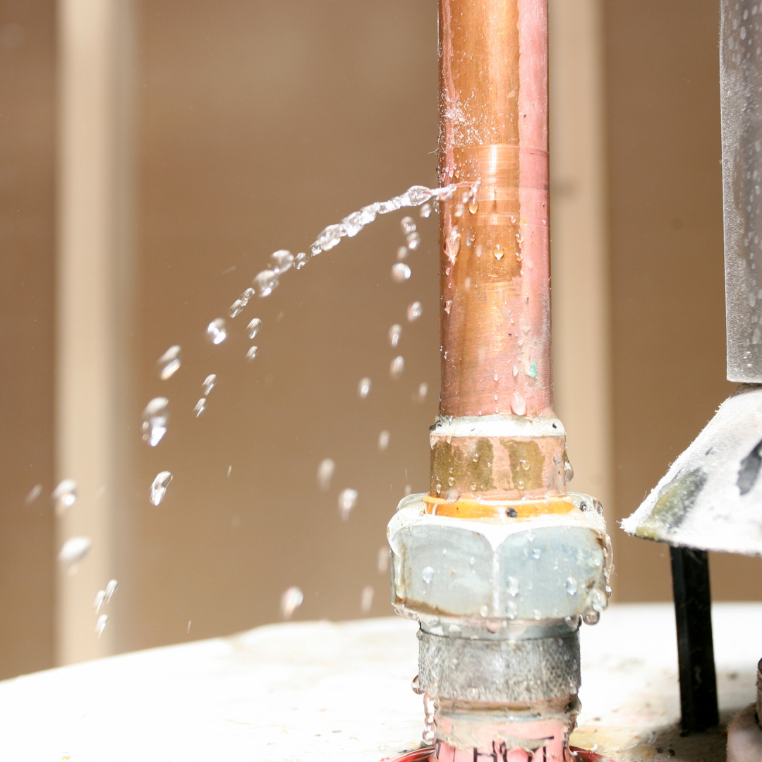 Up close photo of a copper pipe that is leaking water 