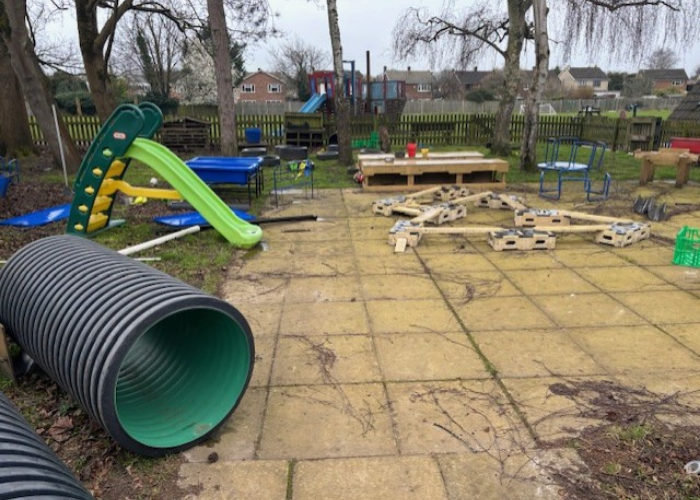 Image of the current outdoor play area featuring an uneven paved flooring scattered with various play equipment.