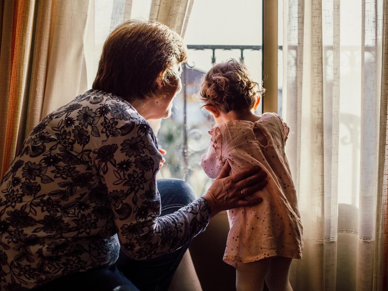 An older woman and a little girl looking out of a window