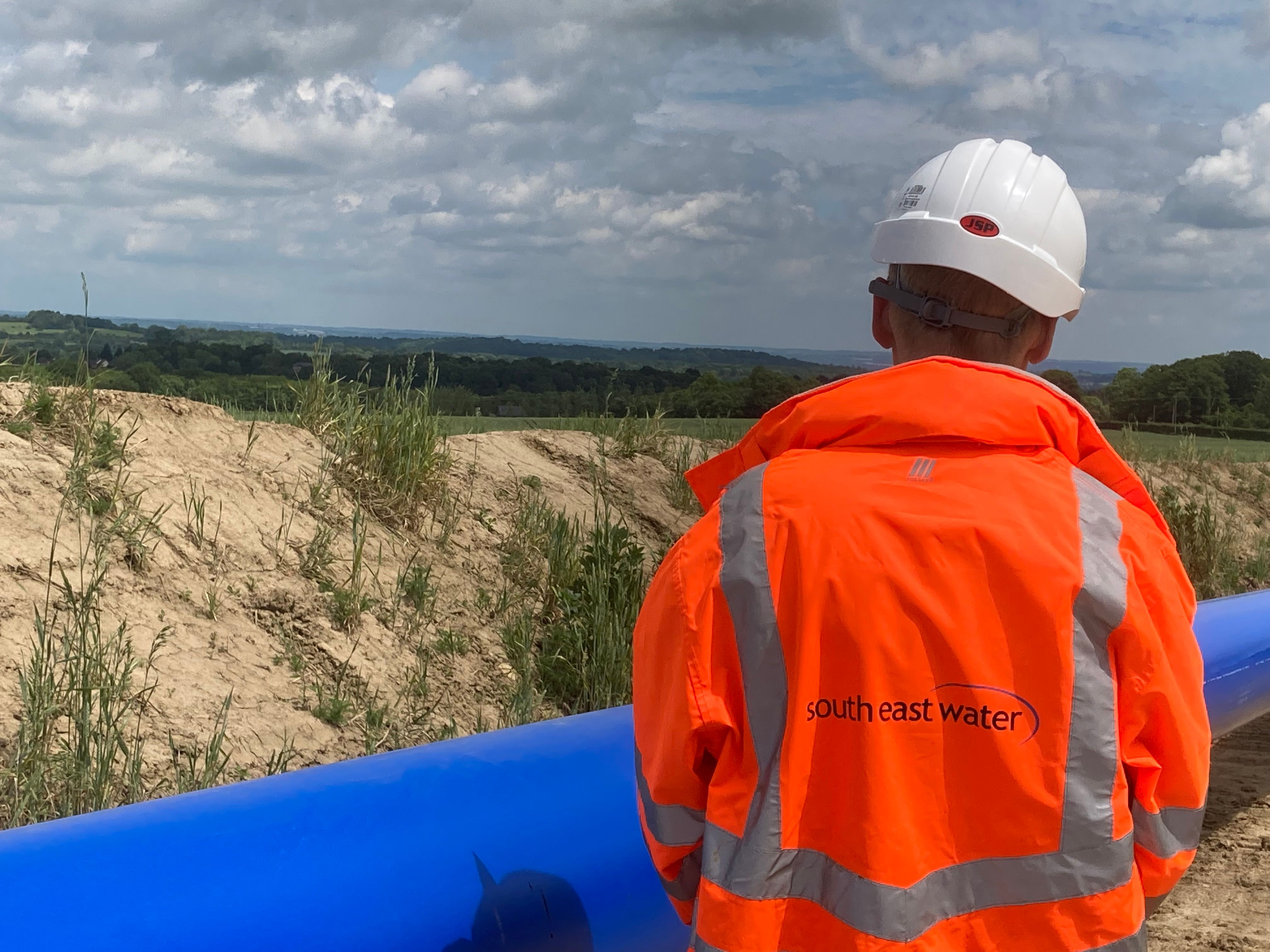 A man looks on over a water pipe and the countryside