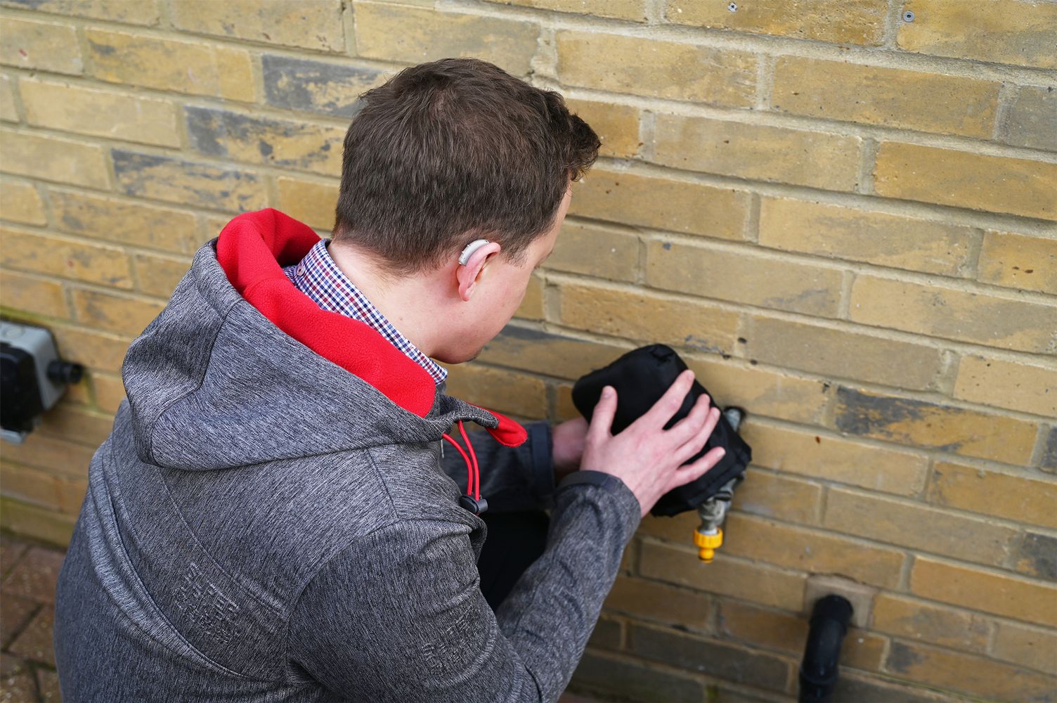 A man protecting an outside tap with a tap jacket in winter