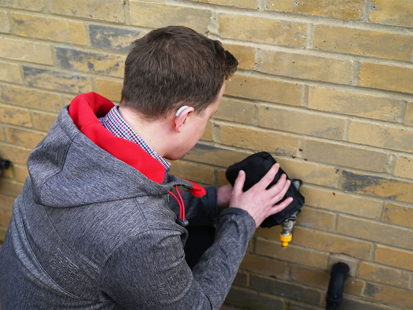 A person protecting an outdoor tap with a tap jacket