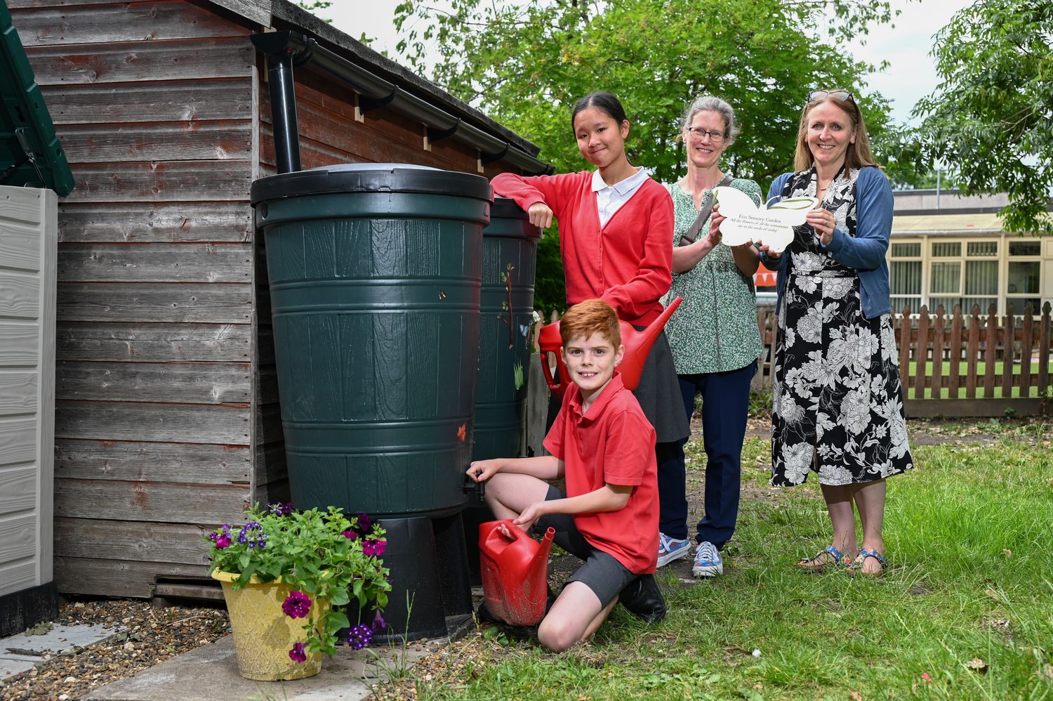 School children and teachers posing with watering cans and water butts