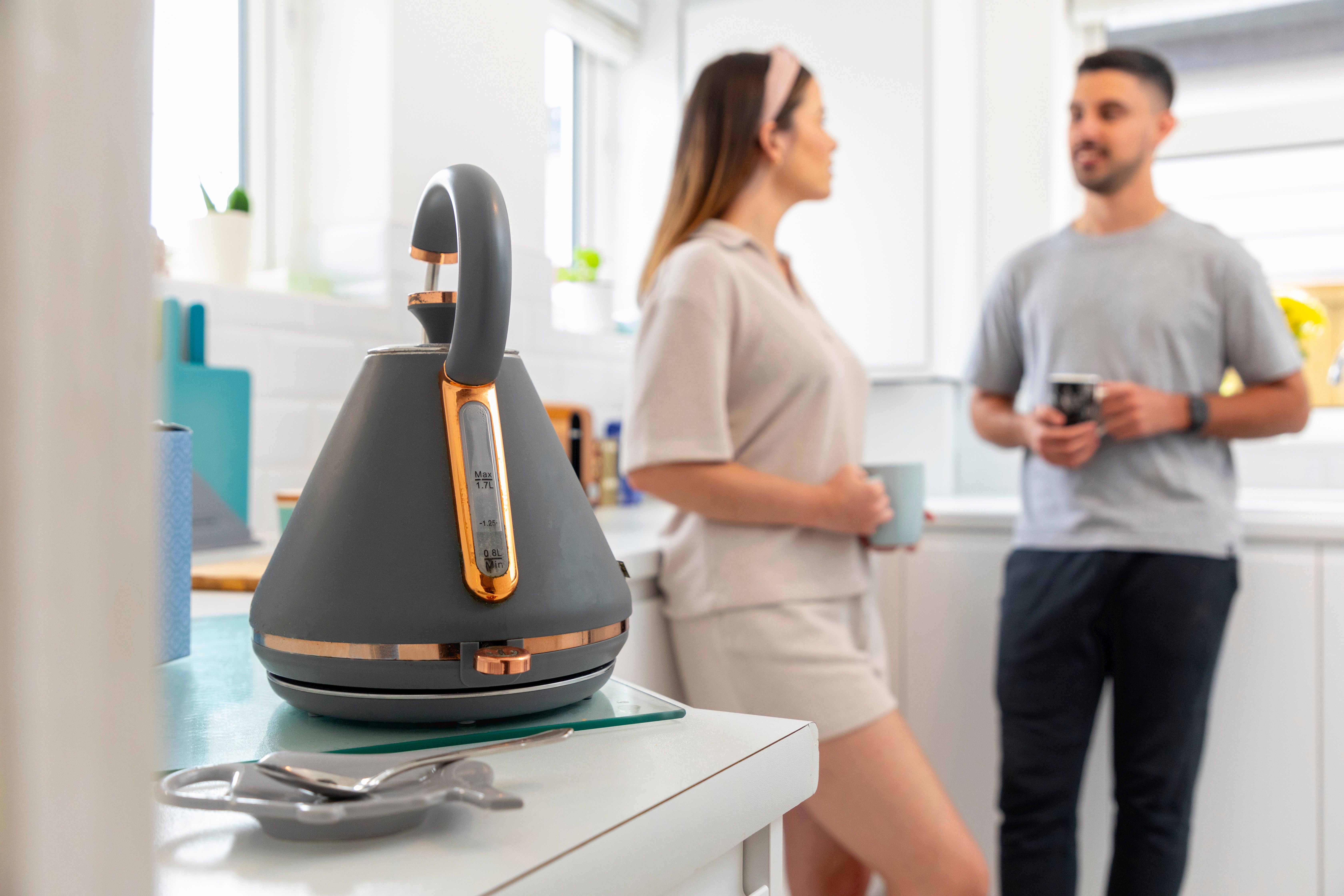 A couple stood in the kitchen chatting with a cup of tea 