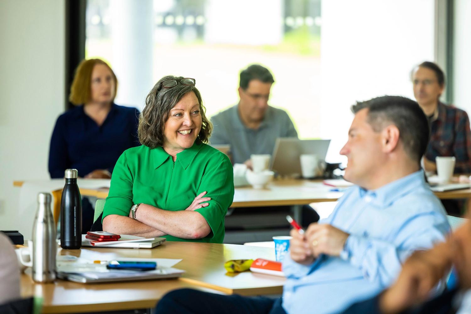 Photo of a number of SEW employees sat chatting at a table at a conference.