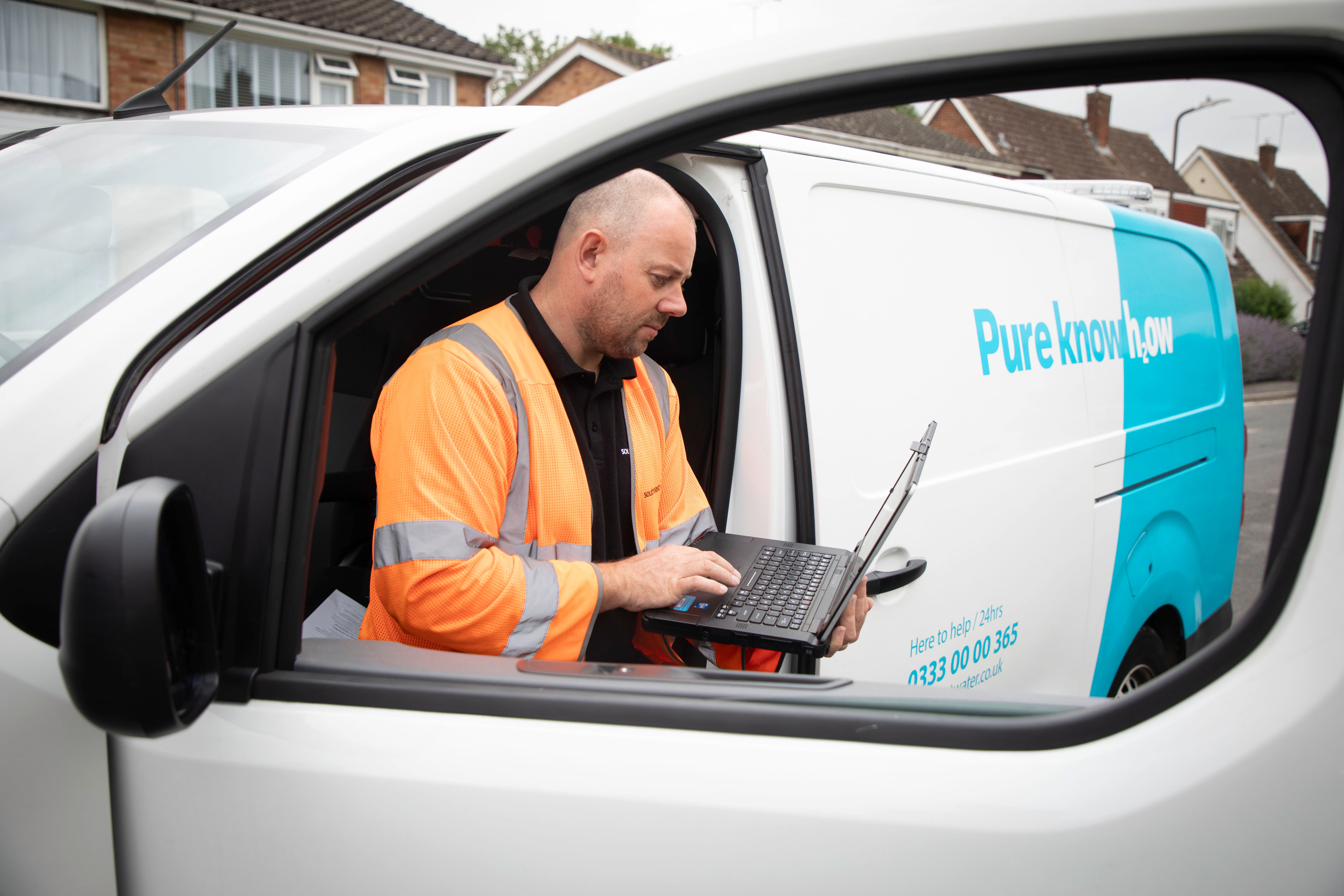 Man in South East Water van with laptop