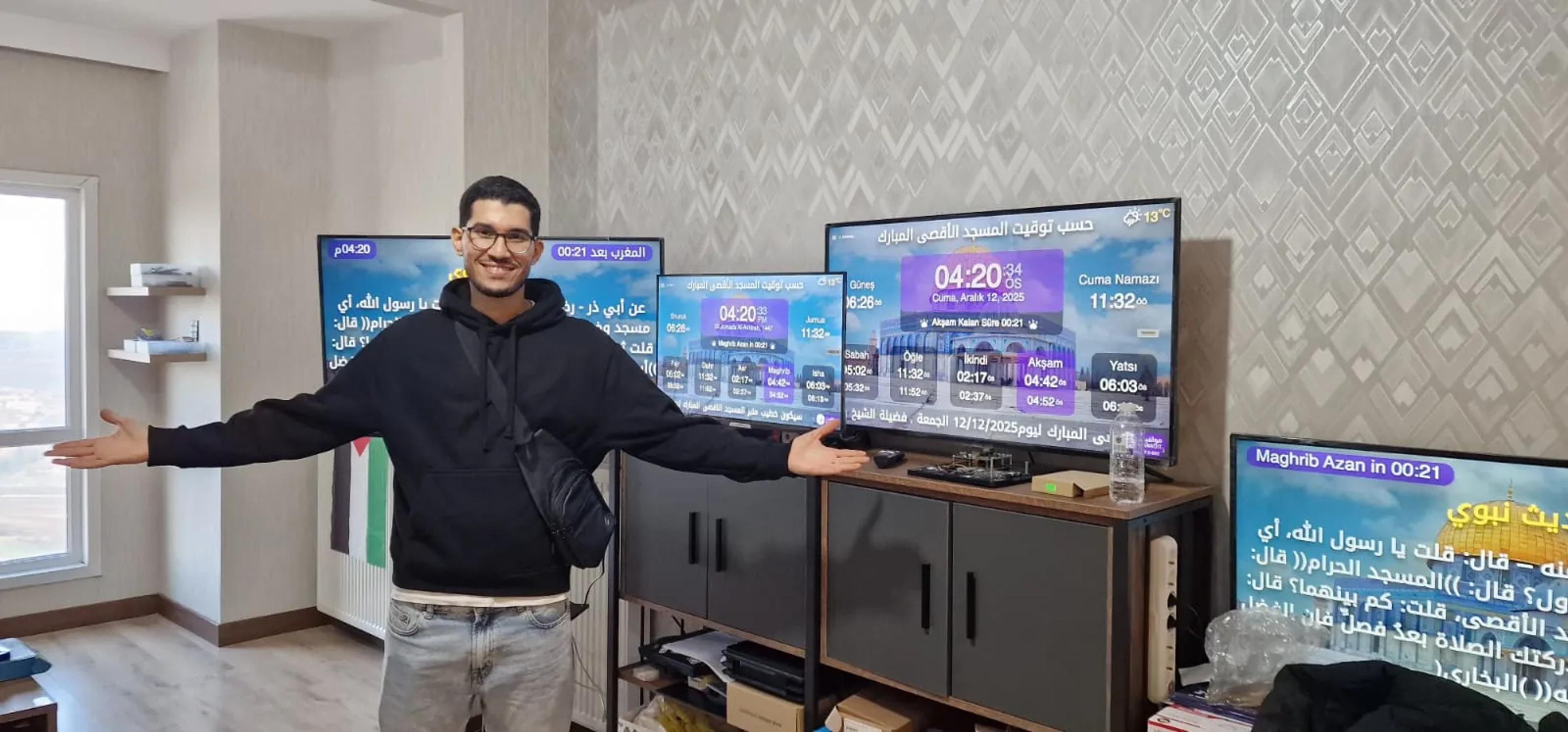 A smiling volunteer in front of several screens running MAWAQIT